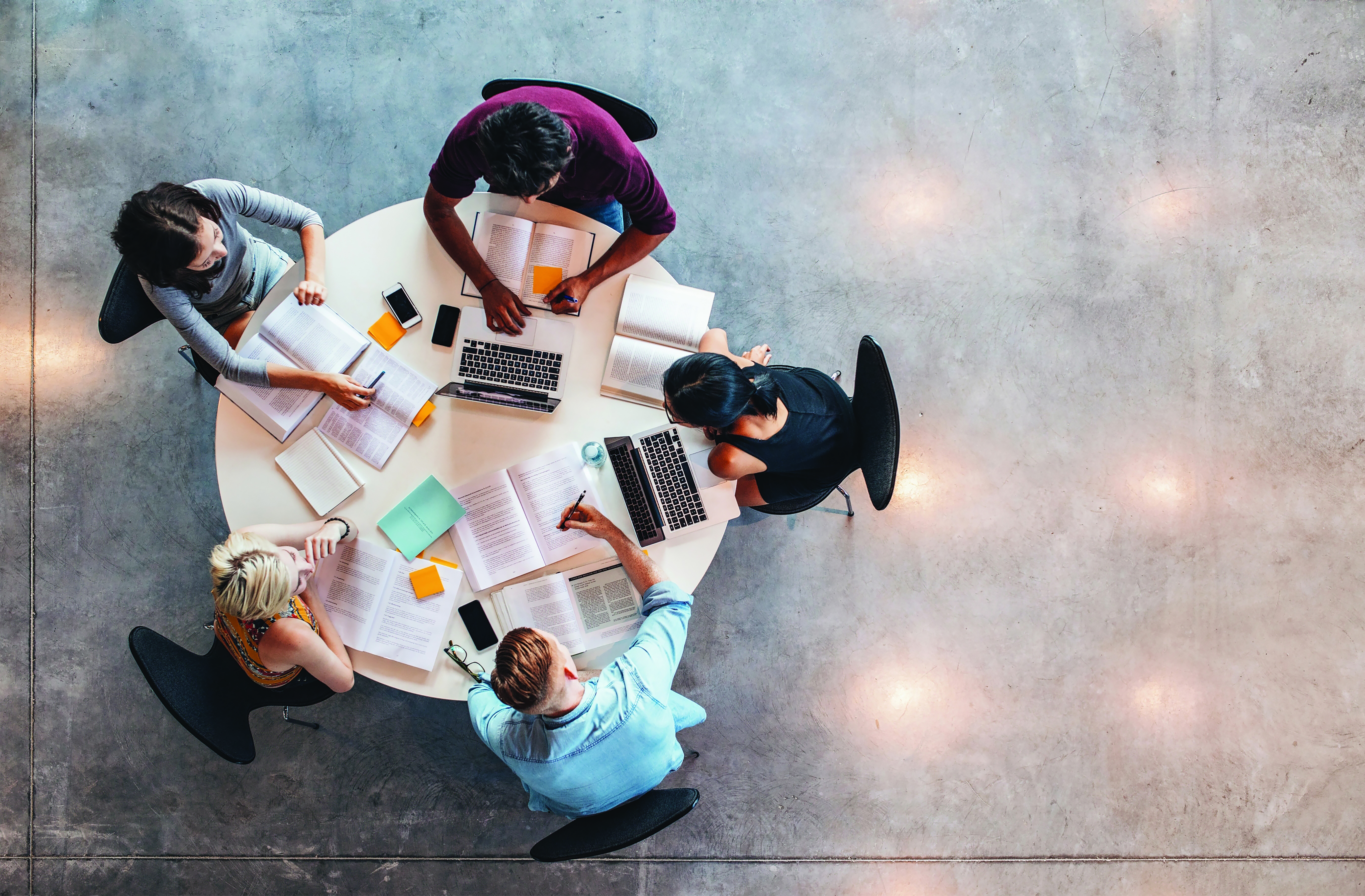 Stock Photo of people collaborating at round table, aerial view from above.